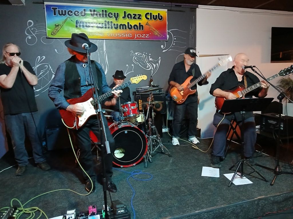 FBI blues band with three guitarists in front of the club banner