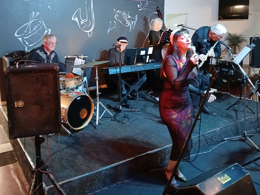 The Early Birds' singer in a red dress, with keyboards, drums and sax