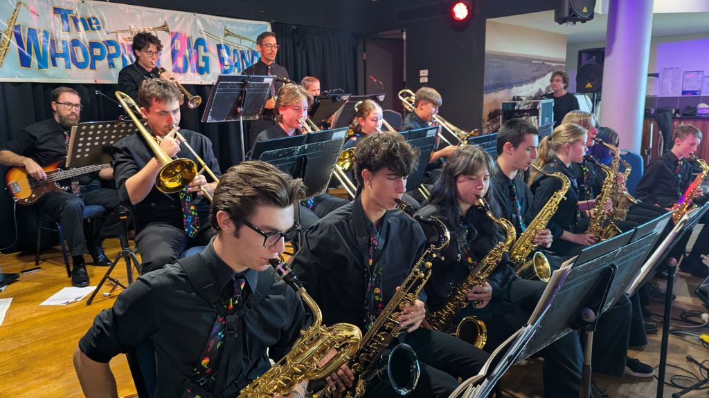 Young saxophone and trombone players of the Whopping Big Band on stage
